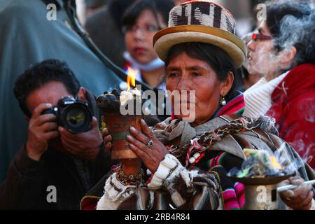 La Paz, Bolivia. 30th May 2014. A press photographer takes a photo of an Aymara spiritual leader or amauta holding a ceramic incense burner (called a keru or k'eru) during the inauguration ceremony of a new cable car system linking La Paz and El Alto. Three lines are being built as part of an ambitious project to relieve traffic congestion, when completed they will form the longest urban cable car system in the world. Stock Photo