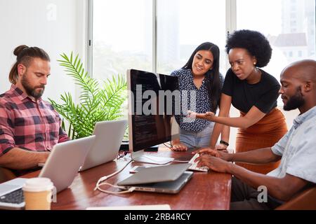 Three developers peer programming together in office, assisting peer review Stock Photo