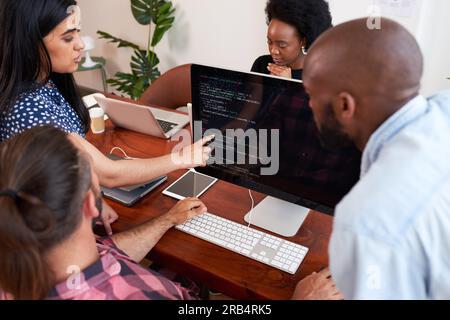 Three developers peer programming together in office, assisting peer review Stock Photo