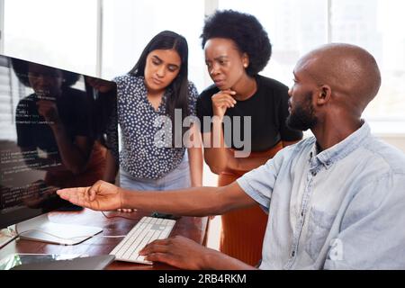 Three developers peer programming together in office, assisting peer review Stock Photo