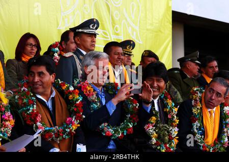 El Alto, Bolivia, 15th September 2014. Bolivian vice president Alvaro Garcia Linera (centre) takes a photo using his smartphone during the opening ceremony of the cable car Yellow Line, watched by president Evo Morales (right). Left of photo is the La Paz Department Governor Cesar Cocarico, on the right is Mi Teleferico CEO Cesar Dockweiler. The Yellow Line is the second of three cable car lines to be opened this year, and is part of an ambitious project to relieve traffic congestion. The first line opened in May, when all three are open they will be the world's longest urban cable car system. Stock Photo