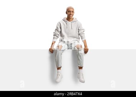 African american gen z man with bleached hair sitting on a blank panel isolated on white background Stock Photo