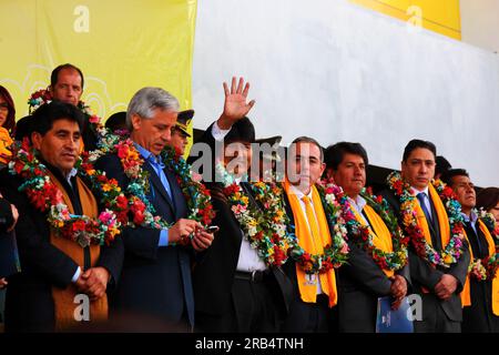 El Alto, Bolivia, 15th September 2014. Bolivian president Evo Morales (centre) waves to supporters during the inauguration ceremony of the cable car Yellow Line. Centre left is the vice president Alvaro Garcia Linera, far left the La Paz Department Governor Cesar Cocarico. The Yellow Line is the second of three cable car lines to be opened this year, and is part of an ambitious project to relieve traffic congestion. The first line opened in May, when all three are open they will be the world's longest urban cable car system. Stock Photo