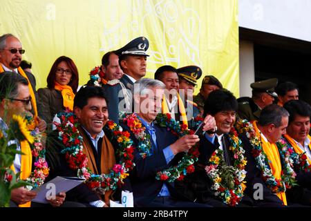 El Alto, Bolivia, 15th September 2014. Bolivian vice president Alvaro Garcia Linera (centre) checks his smartphone during the inauguration ceremony of the cable car Yellow Line. President Evo Morales is to his right, La Paz Department Governor Cesar Cocarico is to his left in the photo. The Yellow Line is the second of three cable car lines to be opened this year, and is part of an ambitious project to relieve traffic congestion. The first line opened in May, when all three are open they will be the world's longest urban cable car system. Stock Photo