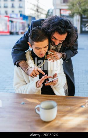 Couple of men using mobile phone watching social networks. Stock Photo