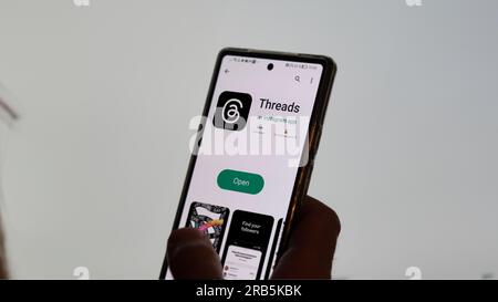 July 7th 2023, a hand holding a phone, the logo of Threads on the screen. On the background the blurry logo of Twitter. Stock Photo