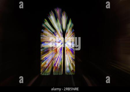 An abstract zoom effect of church stained glass window with multicoloured lines appearing to radiate outwards with a black background. Stock Photo