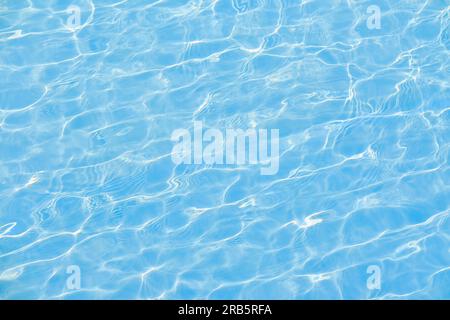 Defocused blurred transparent blue colored clear calm water surface texture with ripple. Shining blue water background. Water in swimming pool. Stock Photo