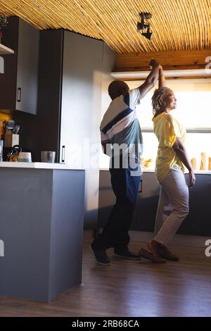 Happy senior african american couple embracing and dancing in kitchen. Senior lifestyle, relaxing and retirement, unaltered. Stock Photo