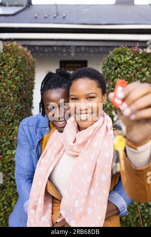 Portrait of african american smiling man embracing girlfriend holding new house keys. Unaltered, love, togetherness, happy, home ownership, moving hou Stock Photo