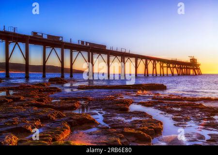 Sunlit historic jetty at Middle camp beach of Catherine hill bay on Pacific coast in Australia. Stock Photo