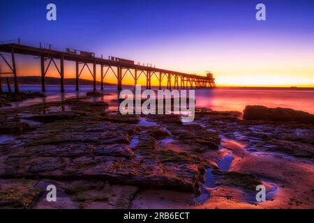 Low tide at scenic sunrise near historic jetty on Middle Camp beach at Catherine Hill bay seascape. Stock Photo