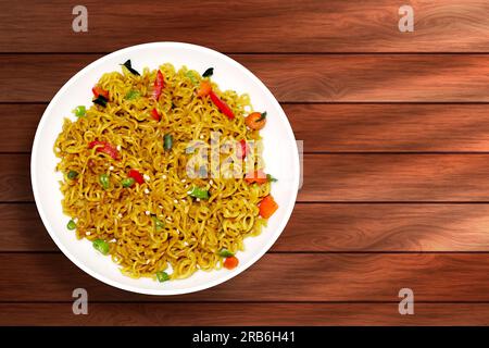 Instant noodles with vegetables in a white plate on a wooden background Stock Photo