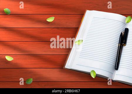 Open notebook with pen and green leaves on wooden table. Stock Photo