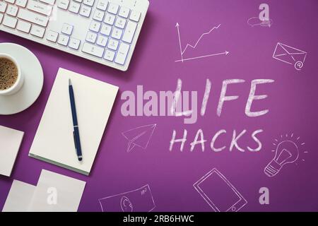 Chalked words Life Hacks and drawings on purple background. Workplace with computer keyboard, cup of coffee and stationery, flat lay Stock Photo