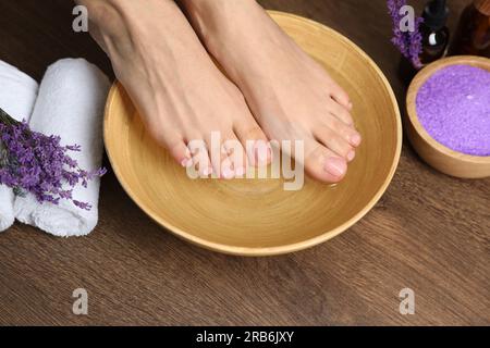 Woman soaking her feet in bowl with water, closeup. Pedicure procedure Stock Photo