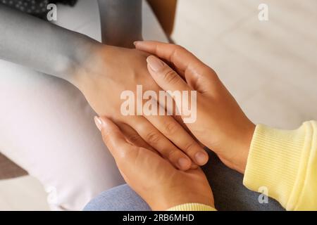 Empathy. Women holding hands indoors, closeup. Transition from black and white to color on photo as symbol of emotional support Stock Photo