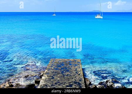 Lanzarote Canary Islands Playa Blanca looking seaward with two  yachts floating on a beautiful blue sea and fluffy cumulus blue sky Stock Photo