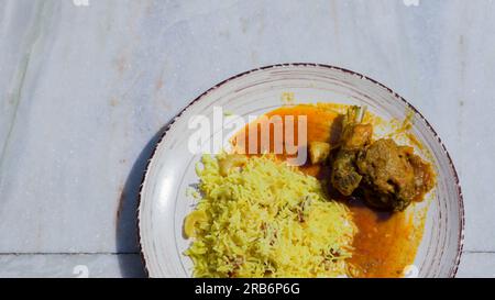 Pulav and chicken curry served on a plate. Traditional Bengali basanti polao or misti polao or fried rice served with chicken gravy dish. Stock Photo