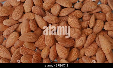 Close-up of organic, peeled almonds falling on table. Stock Photo