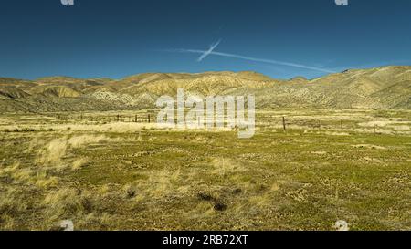 A cross like clouds above the desert field and hills in Carrizo Plain. Stock Photo