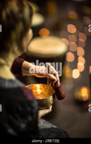 Woman playing on a tibetian singing bowl (shallow DOF; color toned image) Stock Photo