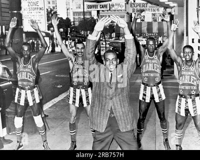 San Francisco, California: January 17, 1962 Chicago Cubs shortstop Ernie Banks leads members of the Harlem Globe Trotters in calesthetics on a downtown street in SF. Banks is on tour with the Globe Trotters and is the master of ceremonies during their pregame show. Stock Photo