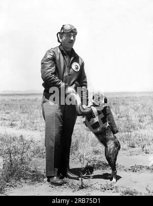 San Diego, California:  c.  1930 Captain E. C. Black, commanding officer of the 11th Bombardment Squadron, with 'Jock', the Scotch terrier who will accompany him on the transcontinental flight of 21 Army bombers, pursuit ships and transport planes, under the command of Major Carl Andrew Spatz. Note the special parachute for the dog. Stock Photo