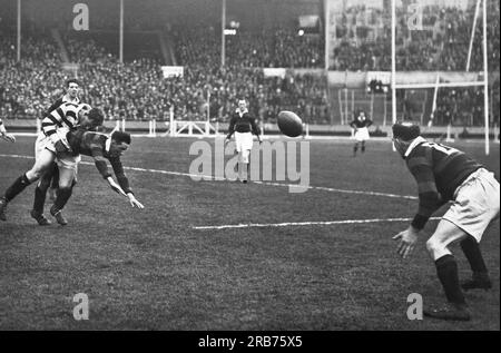 London, England:  1929 For the first time in history, the Rugby League Challenge Cup Final was held at Wembley Stadium between Wigan and Dewsbury. Here a Dewsbury player passes to a teammate just as he is tackled. Stock Photo