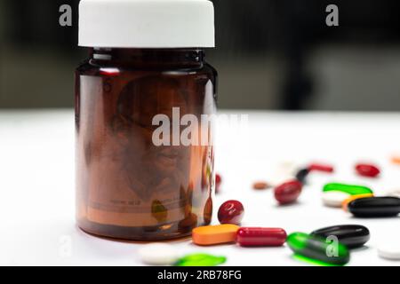 This stock photo shows a 500-rupee Indian banknote inside a tablet bottle with colorful pills on a white background. Stock Photo