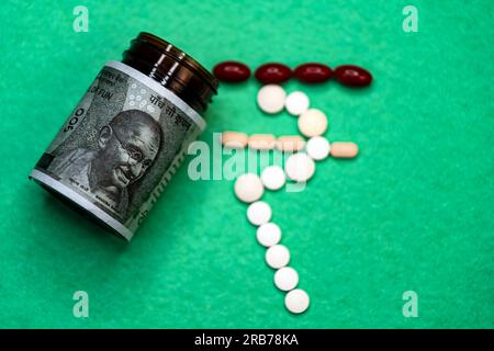 This stock photo shows a bottle of medicine with Indian 500 rupees notes and pills outside. The pills are arranged in the shape of the Indian rupee sy Stock Photo