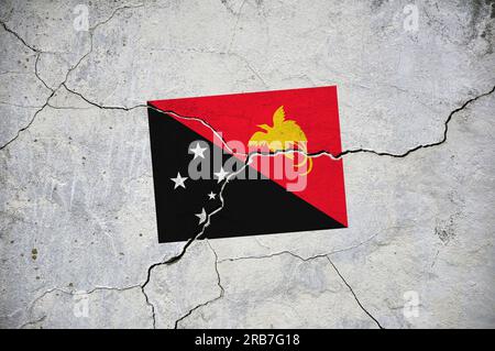 An old image of the flag of Papua New Guinea on a wall with a crack. A crisis. Stock Photo