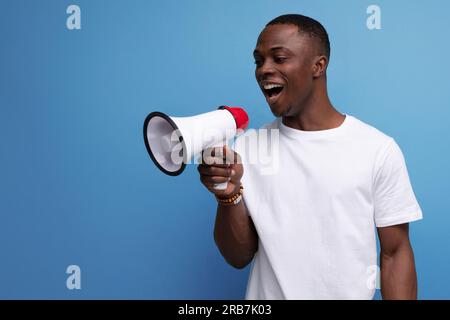positive young american guy in a white t-shirt reports the news using a loudspeaker Stock Photo