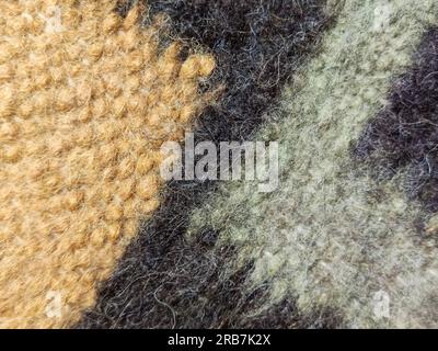 Multicolored woolen knitted fabric with geometric pattern as a background, full frame. Natural wool fabric has a soft and slightly fuzzy texture Stock Photo