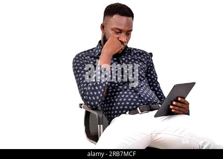 a young bearded man sitting against white background looking at tablet with angry look Stock Photo