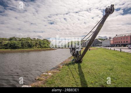 A small crane lift on the quay at Westport in County Mayo, Ireland. On the right are apartments and retail units in Harbour Mill Westport. Stock Photo
