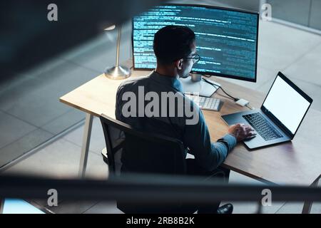 Man, programmer and coding at night on laptop mockup screen for networking, malware or software at the office. Male person, coder or developer working Stock Photo