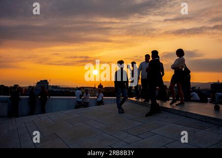 Oslo, Norway, June 20, 2023: Tourists view a sunset from the Oslo Opera House, which was built in 2008 with the intention to allow visitors to walk up Stock Photo