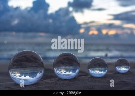 The 4 glass balls are arranged from large to small placed on the beach at  sunrise.