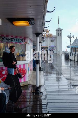 Brighton UK 8th July 2023 - Visitors watch the torrential rain showers in Brighton as thunder storm sweep across parts of the UK today  : Credit Simon Dack / Alamy Live News Stock Photo