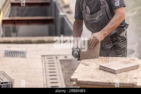 Close up of worker hand using circular saw in the process of cutting stone for paving pavement Stock Photo