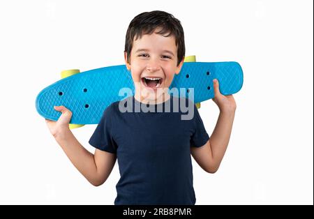 Happy boy laughing and holding bright blue skateboard over vibrant white background isolated Stock Photo