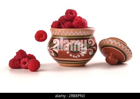 raspberry in clay pot isolated on white, berry falling Stock Photo