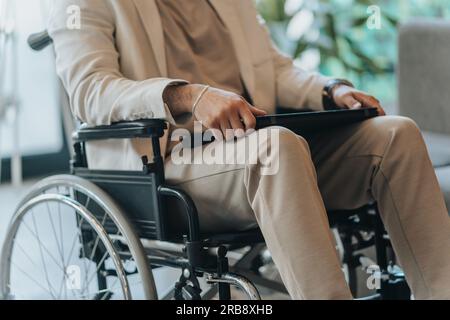 Disabled man on wheelchair in office wearing presentable suit. Adaptation of people with disabilities in society. Recovery and healthcare concept Stock Photo