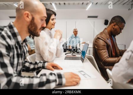 Side view shot of multiracial group of people listening to a presentation, business lecture at the classroom Stock Photo