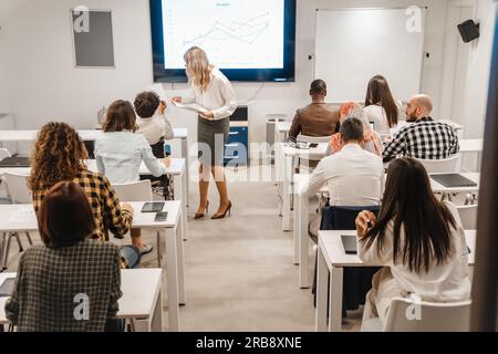 Business teacher, middle-aged female, helping a handicapped male person with the test Stock Photo