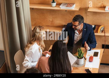 Friends working together and talking at the cafe Stock Photo