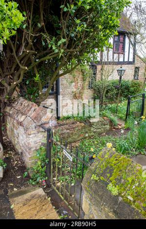old english country cottage in the tudor style, old garden wall and garden gate of a traditional english country garden. Stock Photo