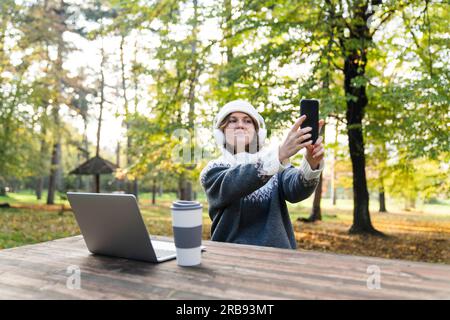 Freelancer working on laptop in autumn park. Stock Photo