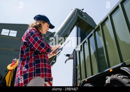 Woman farmer with tablet watching grain loading Stock Photo